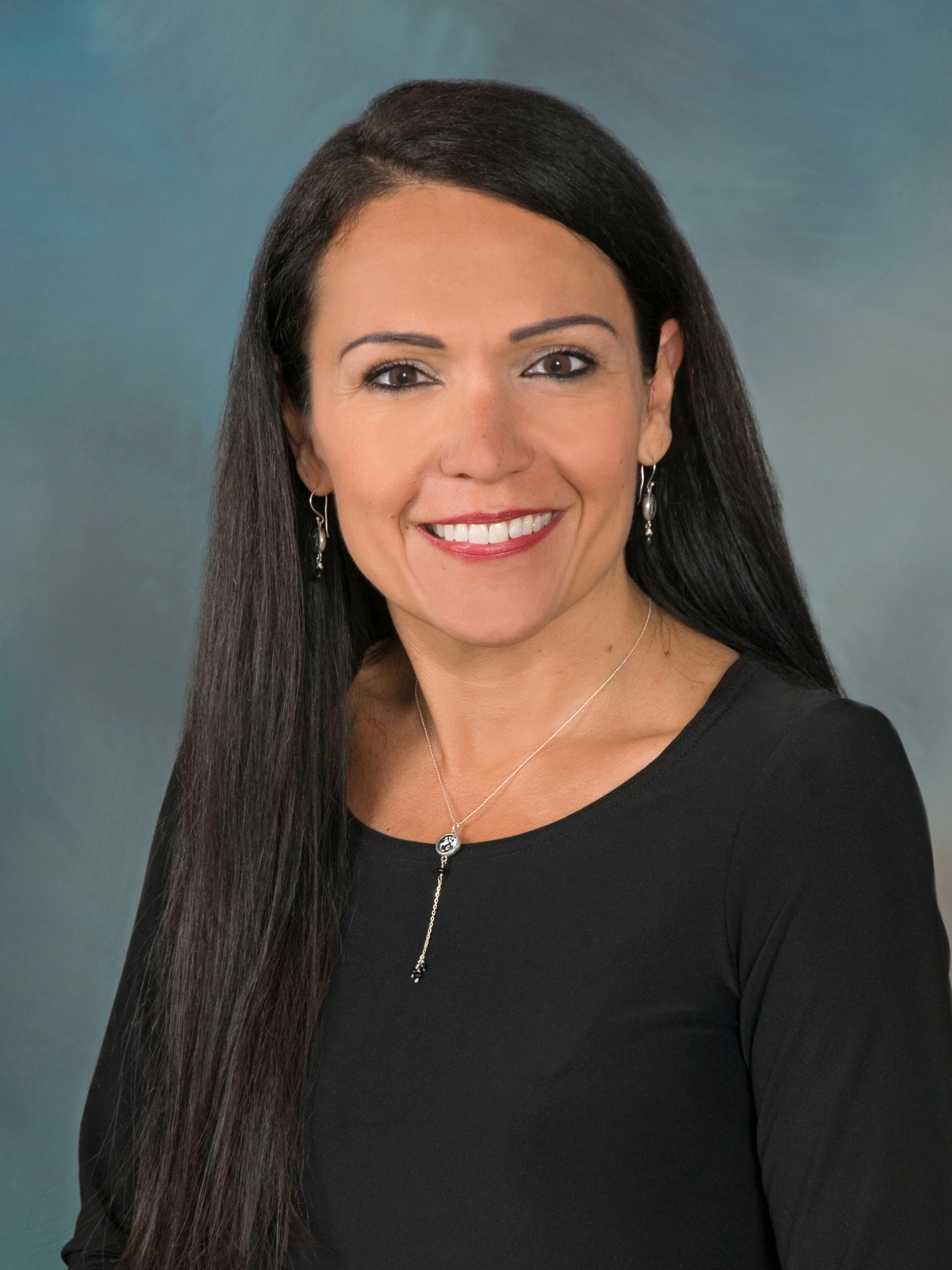 Dr. Rheanna Robinson smiling. She has long, dark hair and is wearing a black shirt.